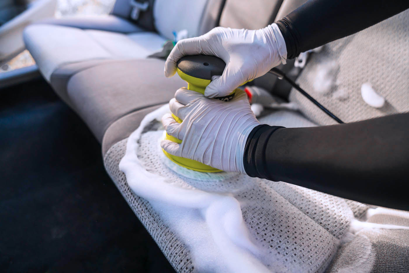 Professional at Dapper Pros doing interior car detailing, giving seats a deep cleaning.