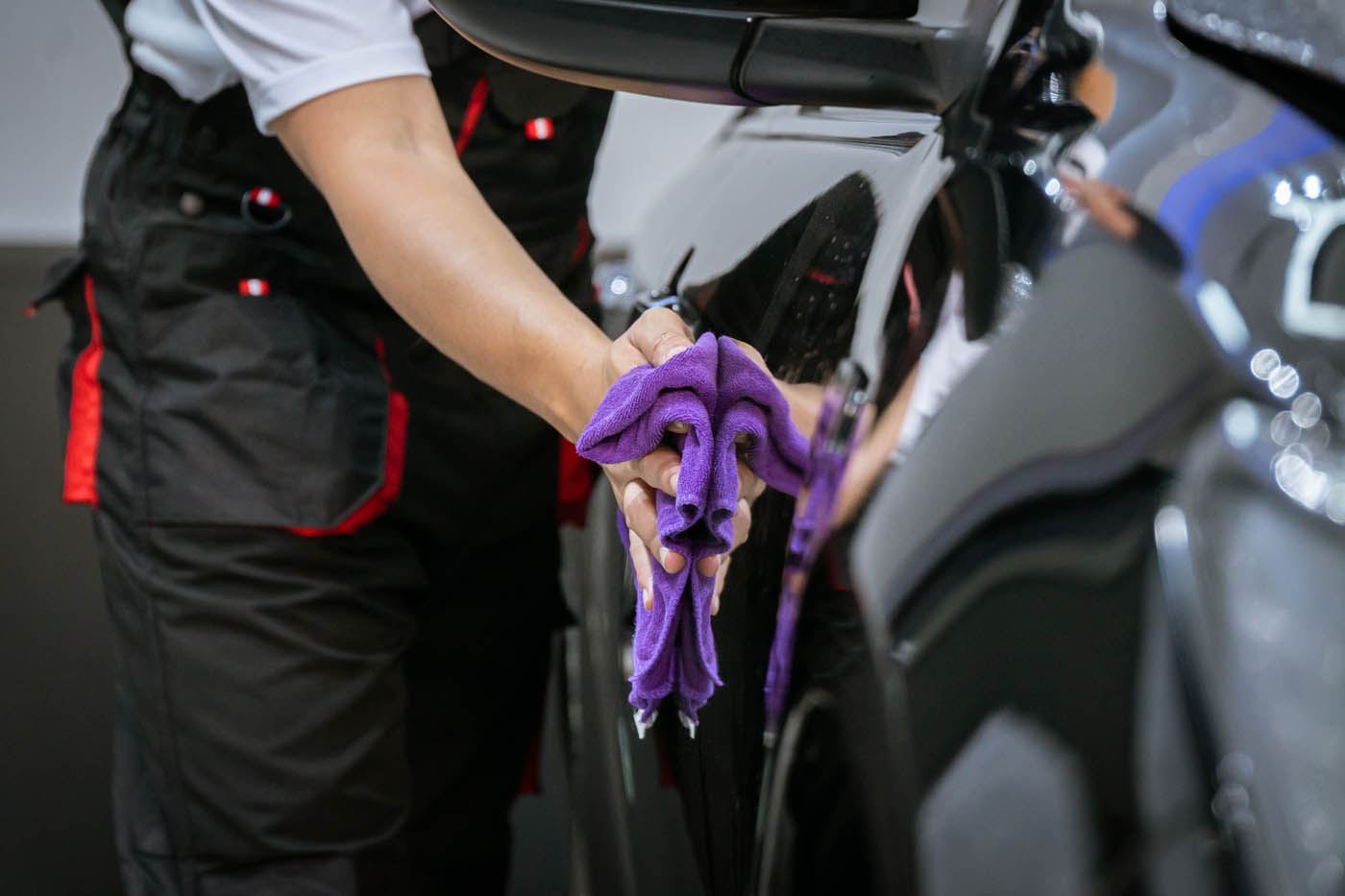 A Dapper Pros employee using a purple towel to provide an exterior car wash.