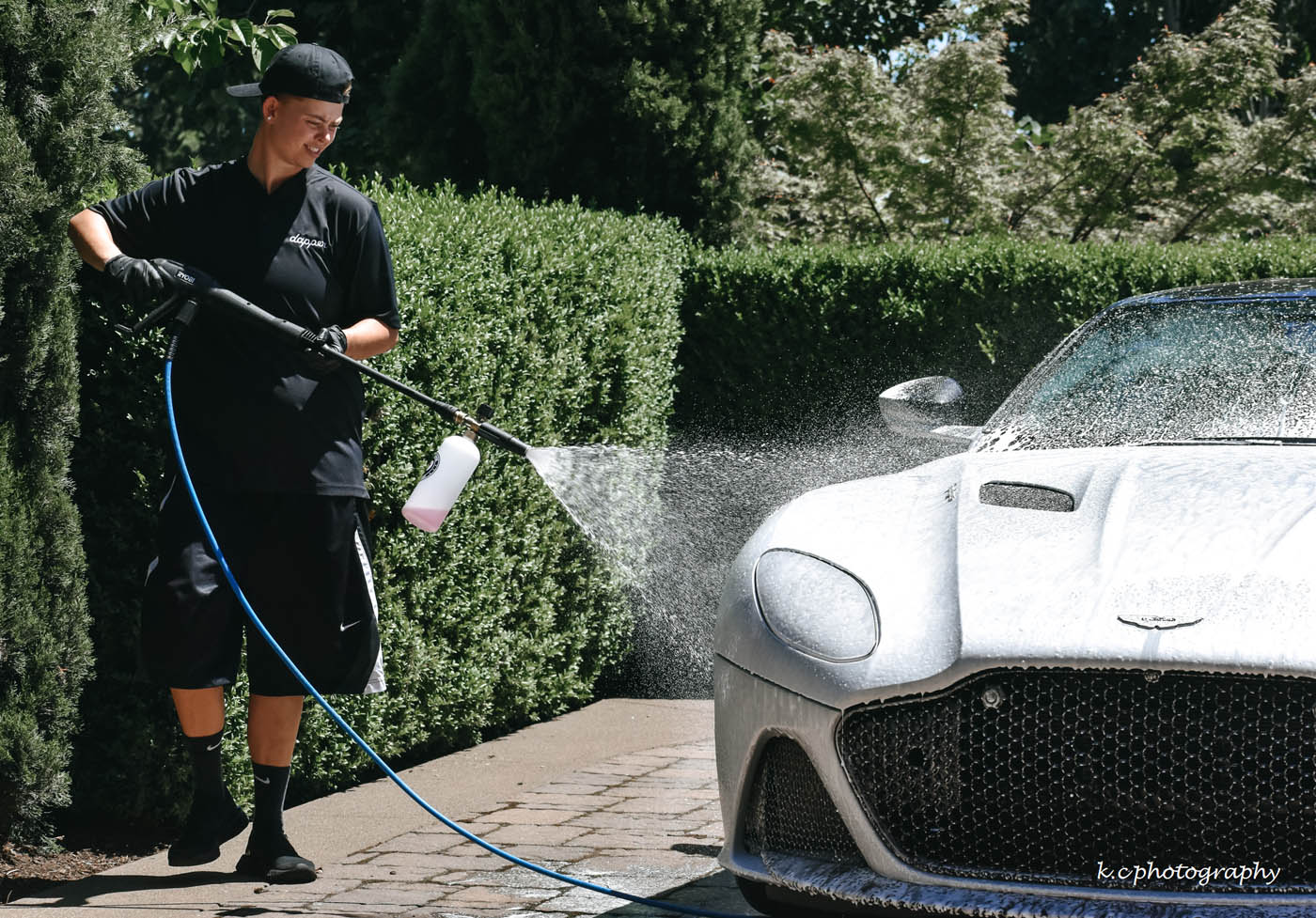 A silver sports car receiving a car wash by a Dapper Pros employee.