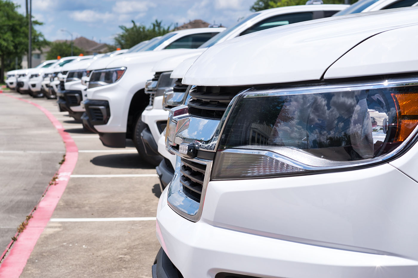 A line of white cars preparing to be detailed by Dapper Pros Washington County's fleet services.